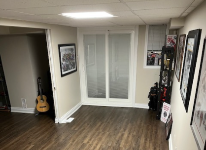 Wide basement with renovated door, lighting, and miscellaneous sports memorabilia